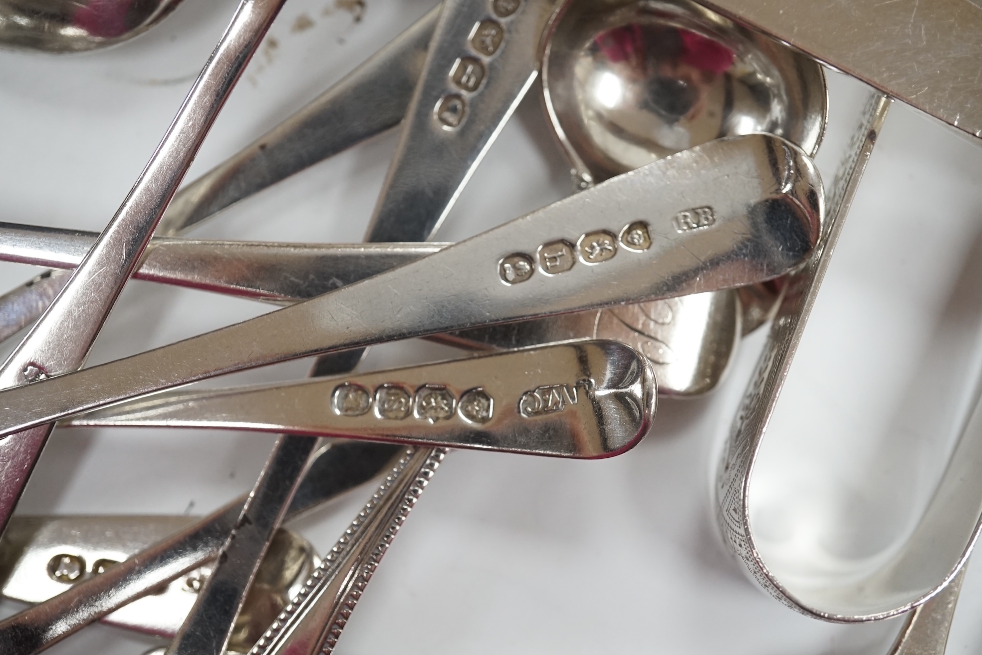 A cased set of six George V silver teaspoons, two cased sets of six silver handled tea knives, fourteen assorted items of 19th century and later silver spoons and a pair of silver sugar tongs. Condition - fair to good